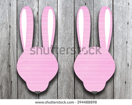 Close-up of two hanged pink blank rabbit silhouette frames with clips against monochrome wooden boards