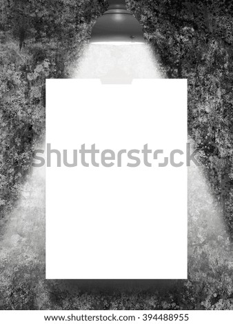 Close-up of one hanged blank frame with lamp against dark grey rough wall background