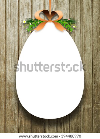 Close-up of one hanged decorated blank Easter egg frame with orange ribbon against brown weathered wooden background
