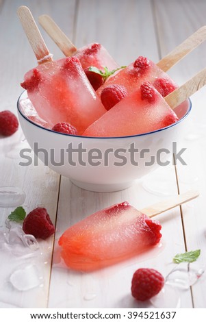 raspberry ice cream pop in white bowl with ice and fresh red berry