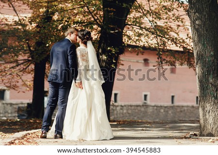 Romantic newlywed couple posing in park near red castle