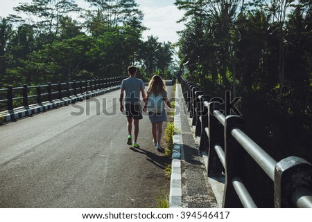 Hipster couple walking on a bridge in the tropics