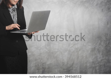 Asia Business woman looking laptop and concrete wall background.Copy space.