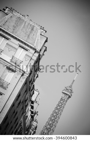 Paris dancing. Inclined Eiffel tower and typical Parisian houses with mansards. Aged photo. Black and white. Vignette.