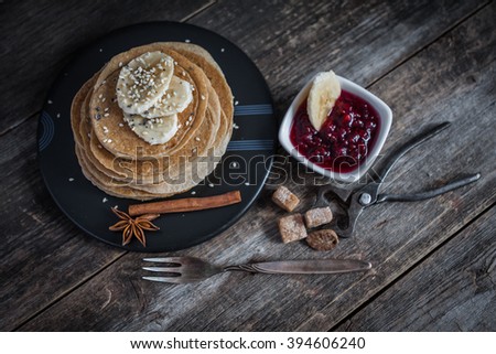 Pancakes with raspberry jam and vintage cutlery on wood background