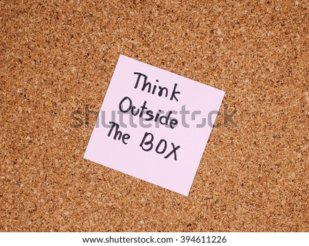 Handwriting word "Think outside the box" on colorful note paper with cork board background