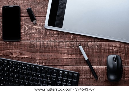 Top view on a wooden desk designer: keyboard, mouse, graphics tablet