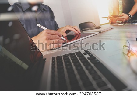 two colleagues Website designer working digital tablet and computer laptop with smart phone and graphics design diagram on wooden desk as concept