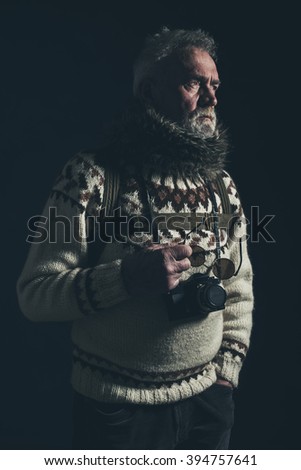 Vintage old mountaineer with knitted sweater, fur collar and SLR camera.