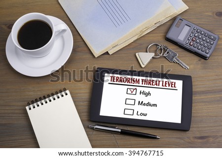 TERRORISM THREAT LEVEL. Text on tablet device on a wooden table