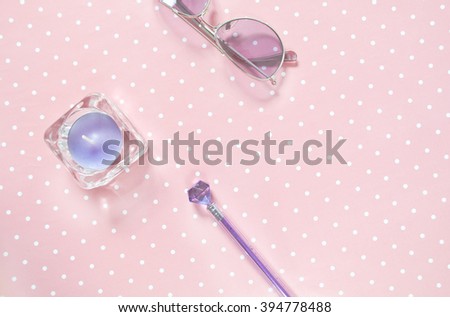 Delicate pink background in white peas with a candle, glasses and pen.
Purple pen, purple candle in a glass candlestick and purple sunglasses on a pink background.