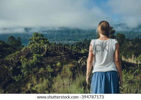Young Woman looking on Batur volcano and Agung mountain view at morning from Kintamani, Bali, Indonesia