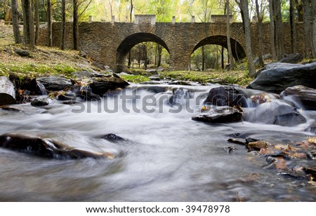 Beautiful old stone bridge over stream water, long exposure