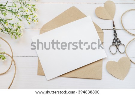 Blank white greeting card with brown envelop and daisy flowers on wooden table with vintage tone Royalty-Free Stock Photo #394838800