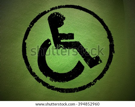 disabled icon sign, green old fabric background.