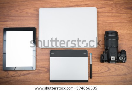 DSLR digital camera with tablet and notebook laptop on wooden desk table