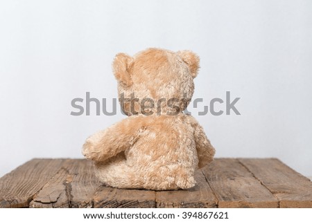 Teddy Bear toy alone on wood.
