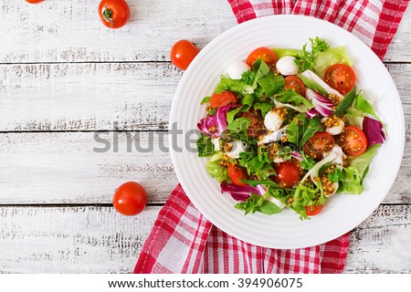 Dietary salad with tomatoes, mozzarella lettuce with honey-mustard dressing. Top view Royalty-Free Stock Photo #394906075