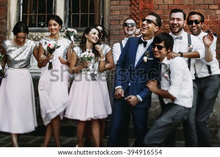 Cheerful & fun groom with bridesmaids & groomsmen posing outdoors