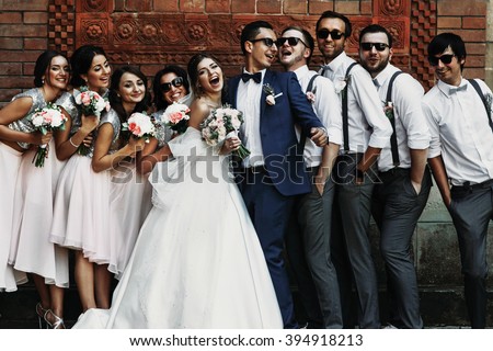 Cheerful & fun groom with bride, bridesmaids & groomsmen posing outdoors