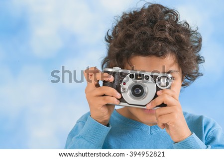 Little boy with an old camera shooting outdoor. 