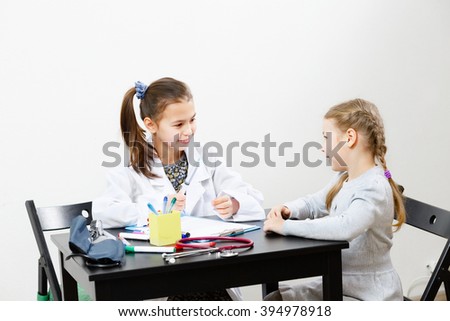 The doctor is receiving a patient, the conversation in the cabinet. girls play Royalty-Free Stock Photo #394978918