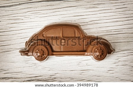 Little chocolate car figure on wooden background. Sweet art food. Royalty-Free Stock Photo #394989178