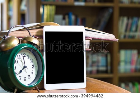 Tablet mockup with vintage alarm clock and the old book in library, Education concept