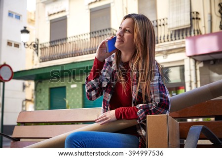 Young architect talking mobile sitting on bench in the city