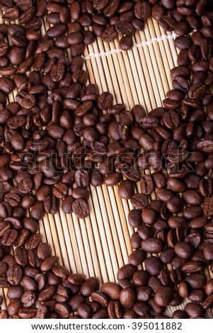 Coffee beans are laid out on a table on a straw or wooden stand. Coffee is laid out in the shape of a heart. Good for Valentine's day, at the time of declaration of love, makes an offer