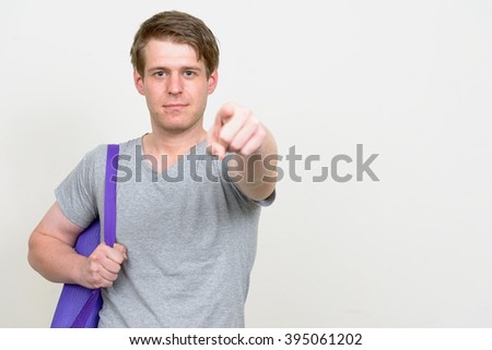 Man holding exercise mat and pointing finger at you