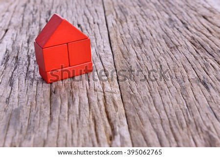 red model of house as symbol on wooden background