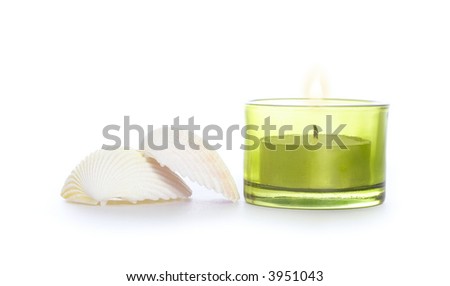 shells and candle in green glass on white background