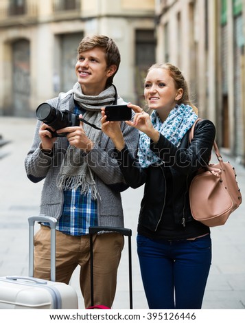Young couple sightseeing and taking pictures on a camera and smartphone 