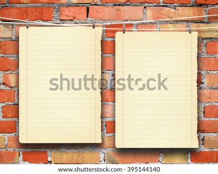 Close-up of two hanged blank old vintage paper sheet frames with pegs against orange brick wall background