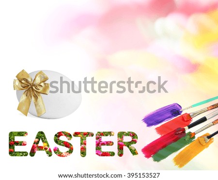 Colorful beautiful flowers with Word EASTER and Easter egg. Natural motion blurred colors background with art brushes and paints. EASTER holiday decoration abstract
