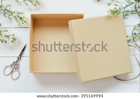 Opened brown gift box on wooden background with white daisy flower and vintage tone Royalty-Free Stock Photo #395169994