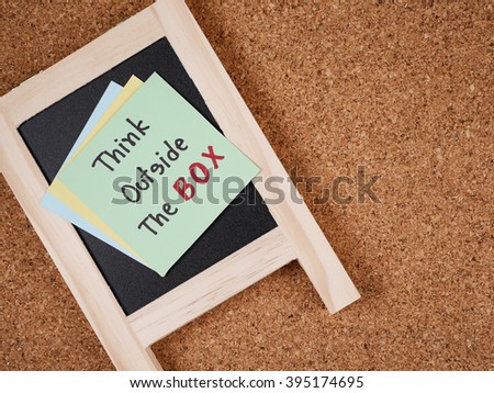 Handwriting word "Think outside the box" on colorful note paper and blackboard with cork board background