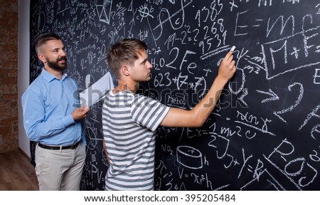 Teacher and student writing on big blackboard with mathematical 