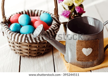 Multicolored Easter eggs in wicker basket on white wooden background