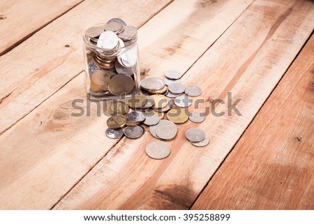coins money in glass bottle on wooden background
