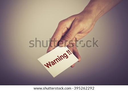 " Warning " word on card hold by man