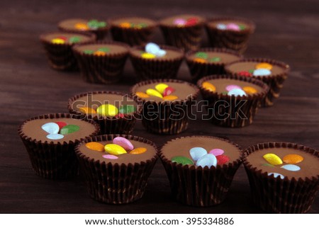 Chocolate candies with colored filling on the wooden background.