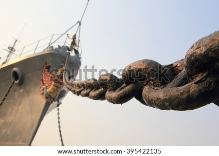 Prow old rusty grey military ship with the metallic anchor chain diagonally