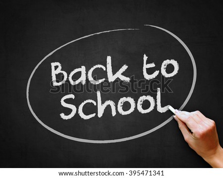 A hand writing 'Back to School' on chalkboard.