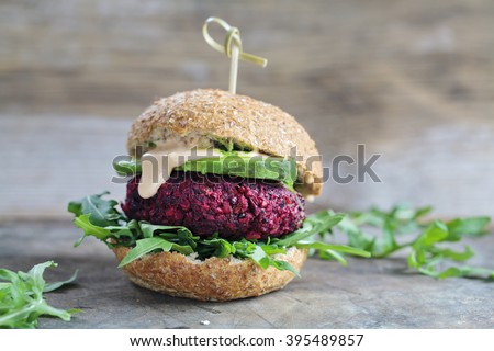 Vegetarian burger made of beetroot, broccoli and chickpeas with avocado and arugula Royalty-Free Stock Photo #395489857