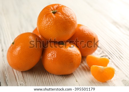 Five fresh delicious unpeeled tangerines with slices on the white wooden table, close up