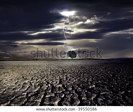 Cracked land and the lightning strikes on the distant tree Royalty-Free Stock Photo #39550186