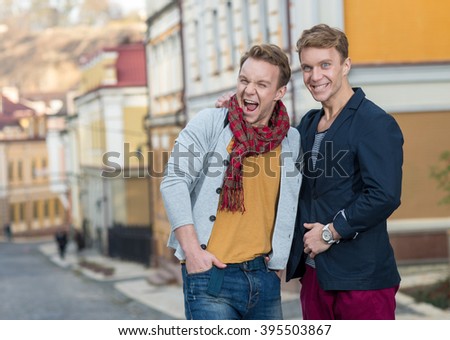 Cheerful day of twin brothers. Two stylish and handsome adult twin brothers are walking around and having fun together. Twins outdoor fashion style concept.