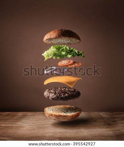 Delicious burger with floating ingredients on the wood table background